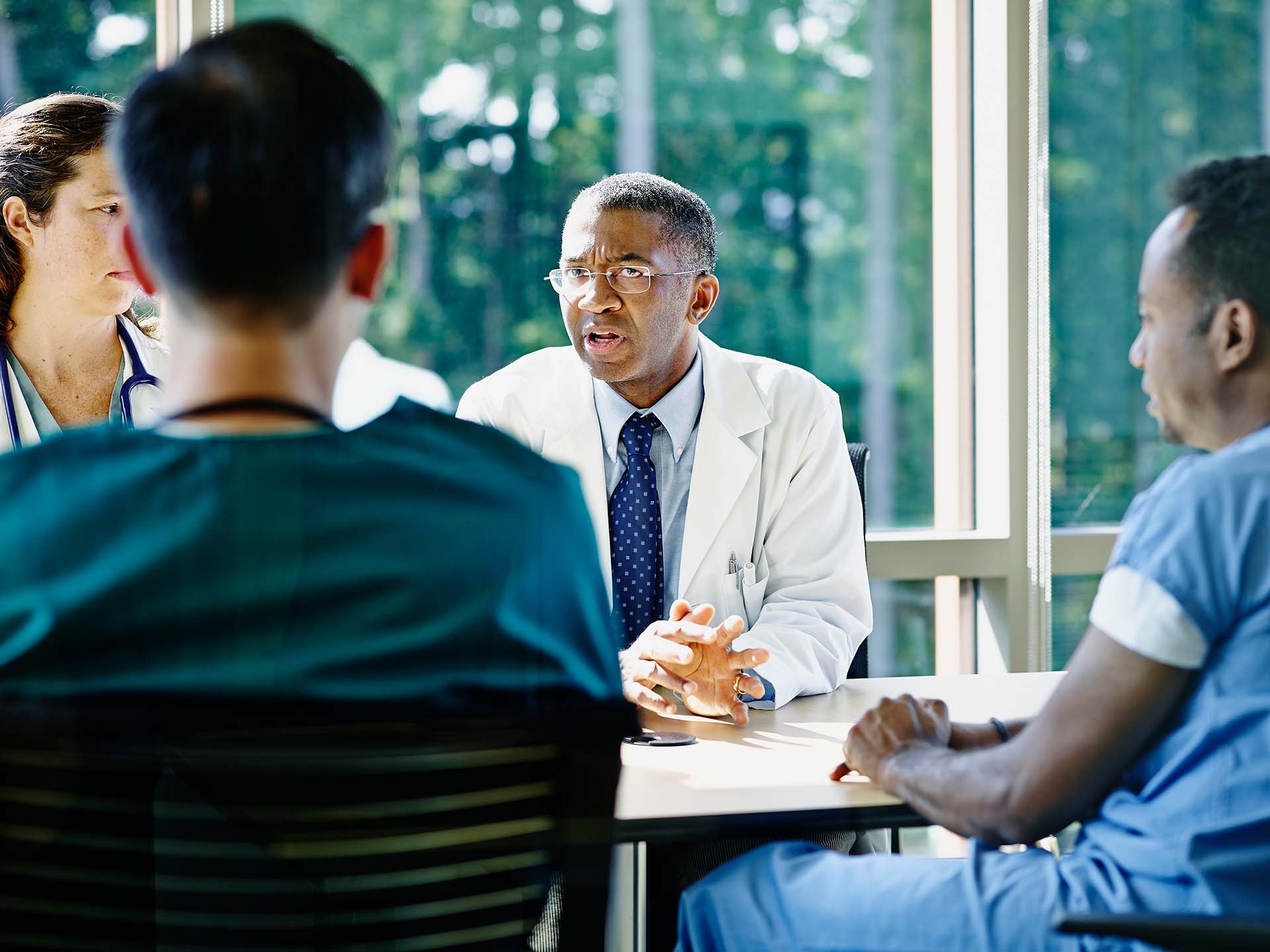 Mature male doctor leading discussion in medical team meeting in conference room in hospital