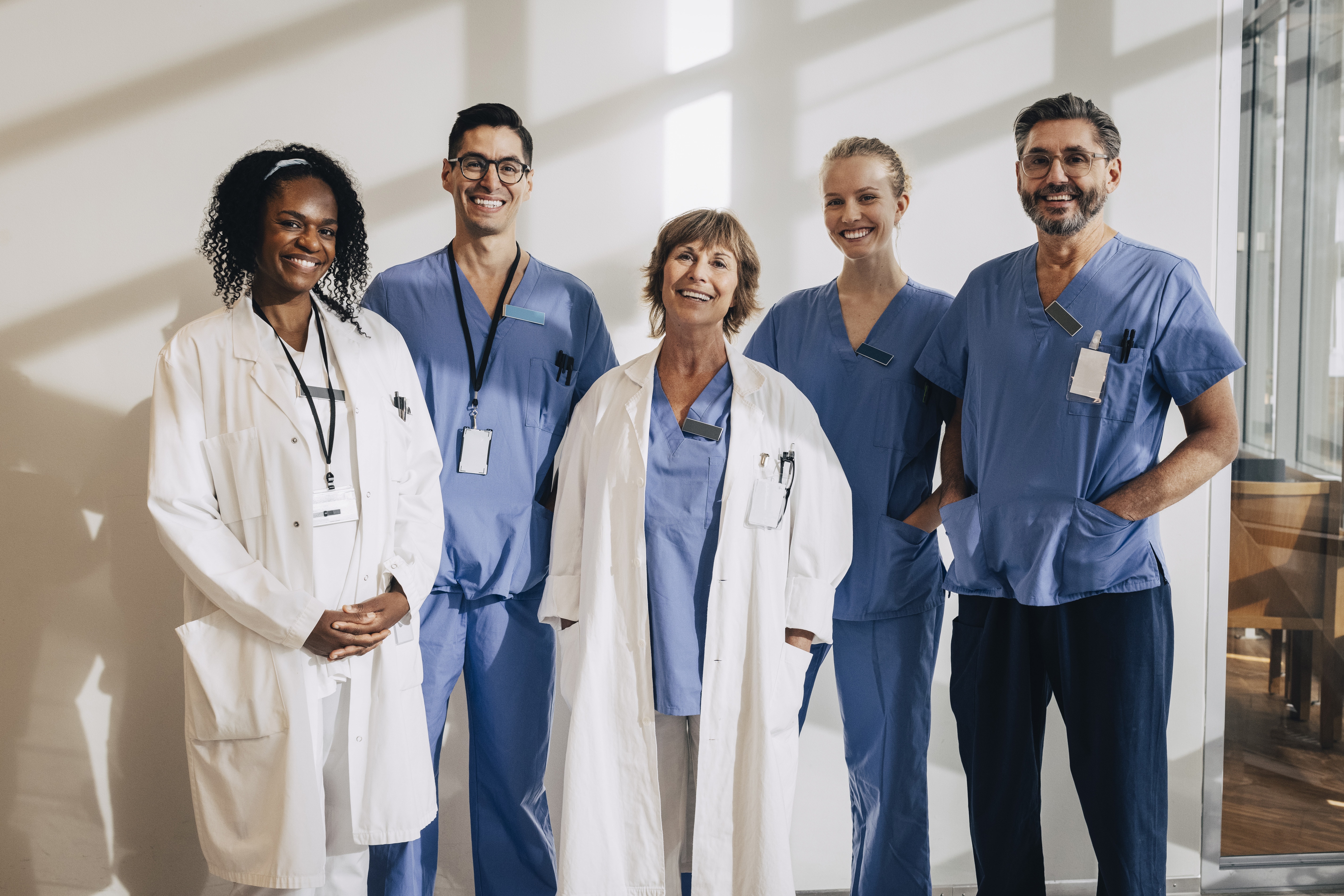 Sunlight Falling On Happy Multiracial Medical Professionals Standing In Hospital